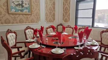 Comedor con una mesa redonda, servilletas rojas y sillas blancas.