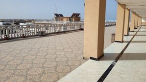 Een overdekt buitengebied met patroonvloer, een witte balustrade en beige pilaren.