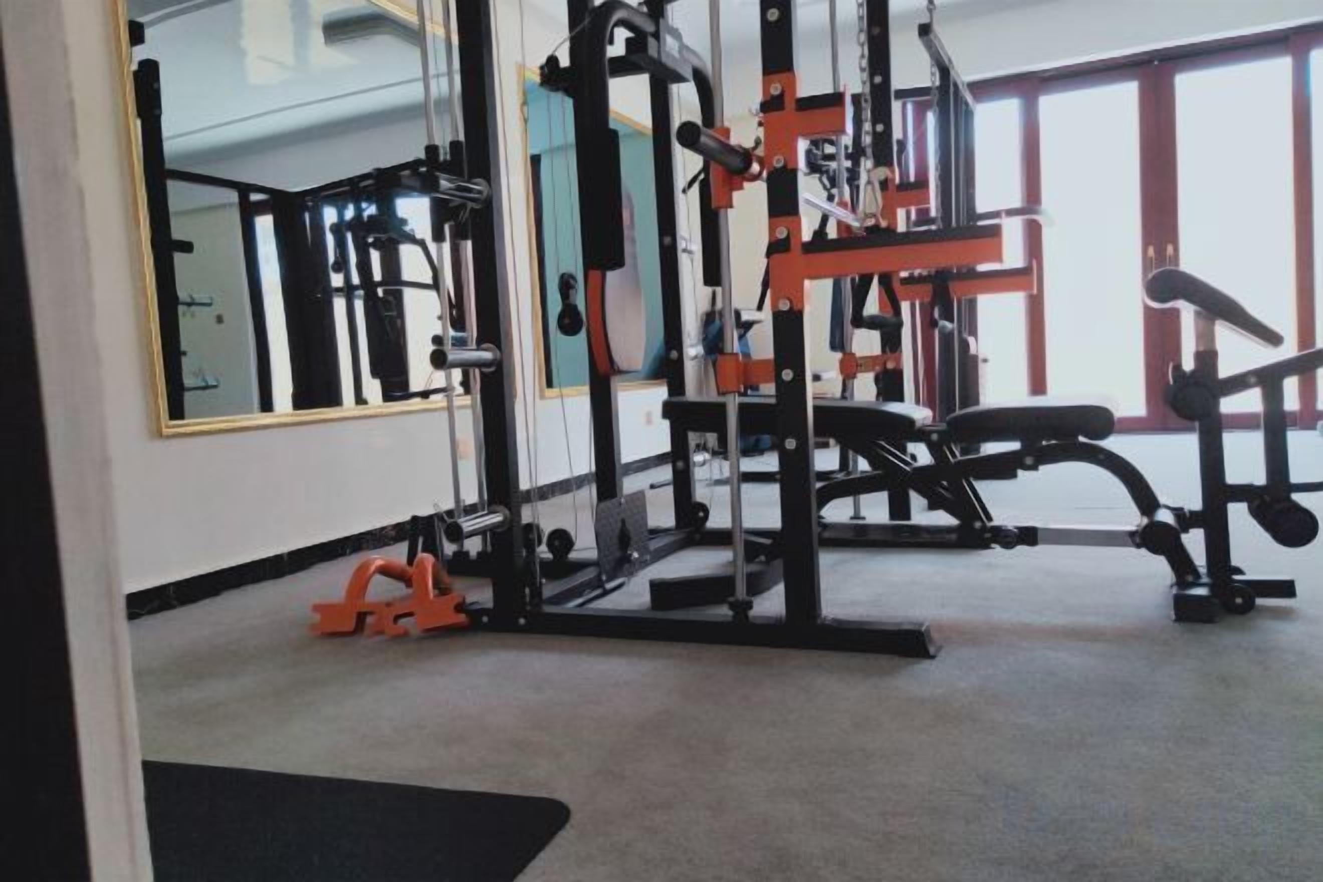 A gym with exercise equipment, large windows, and a mirror.