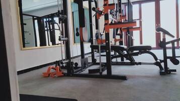 A gym with exercise equipment, large windows, and a mirror.