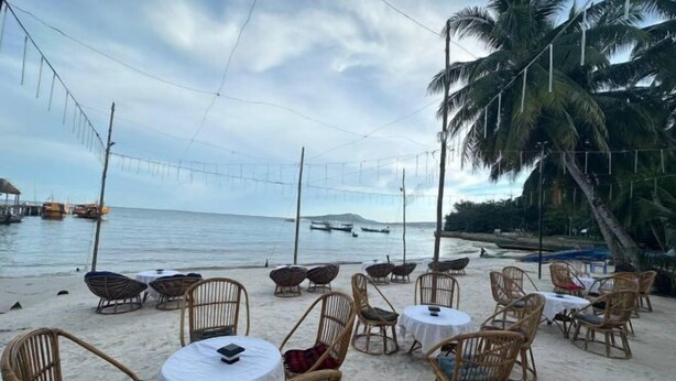 A beachside dining area with wicker chairs and tables, overlooking the sea. - Koh Rong Home Stay (Sihanoukville)