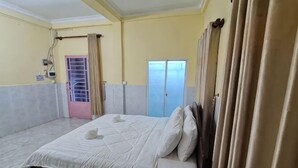 A bedroom with a bed, curtains, a wardrobe, and a door. - Koh Rong Home Stay (Sihanoukville)