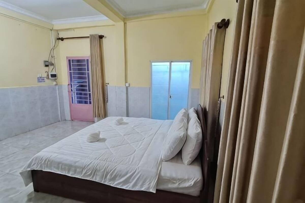 A bedroom with a bed, curtains, a wardrobe, and a door.