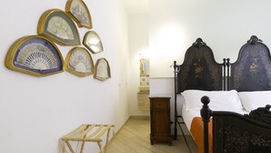 A bedroom with a bed, a bedside table, a lamp, and a wall-mounted drying rack. - Fico d'India by Wonderful Italy (Siracusa)