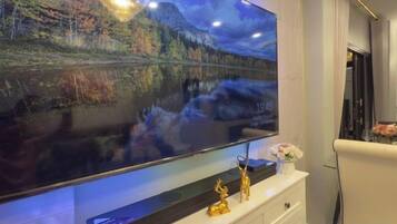 A flat-screen TV mounted on a wall, a white console below it, and a decorative item on the console.