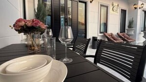 A dining area with a table set for two, featuring white plates, a vase with flowers, and wine glasses. - ChillTime (Chiang Rai)