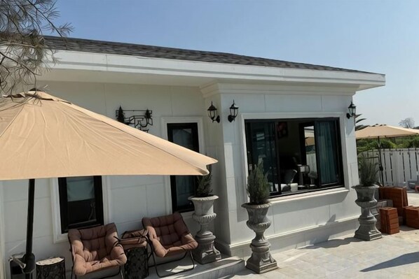 A white building with a covered patio area, outdoor seating, and large windows. - ChillTime (Chiang Rai)
