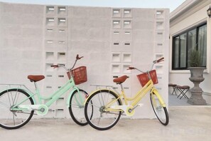Tre cyklar parkerade framför en byggnad med en fasad av betong.