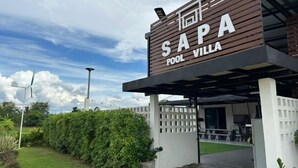 Une enseigne pour la « SAPA POOL VILLA », au design moderne, avec une entrée abritée et un jardin bien entretenu.
