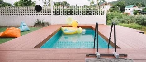 A swimming pool with a yellow inflatable duck, surrounded by a wooden deck and a white fence.