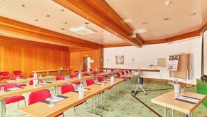 Ett konferensrum med långa bord, röda stolar, en whiteboard och en projektor.