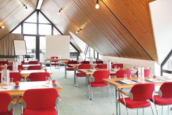 Ein Konferenzraum mit Tischen, Stühlen, einer Tafel und einem großen Fenster.