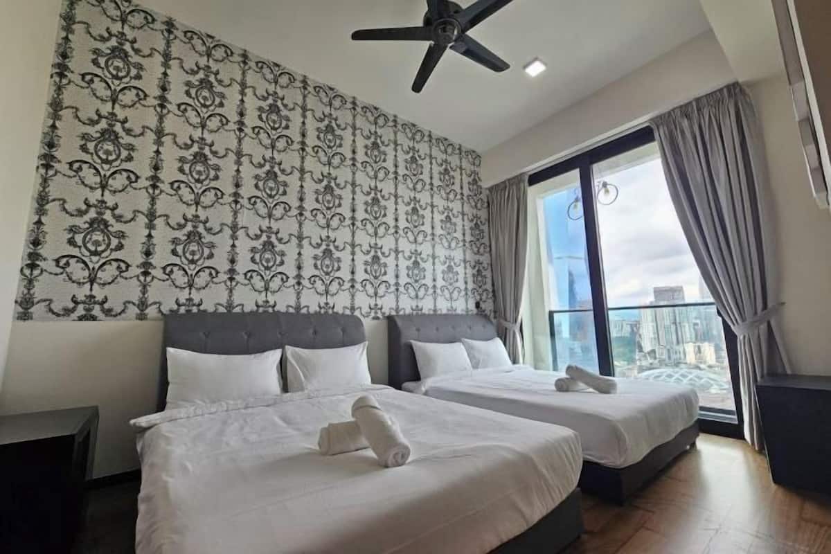 Une chambre d’hôtel avec deux lits, un ventilateur de plafond et une grande fenêtre avec des rideaux.