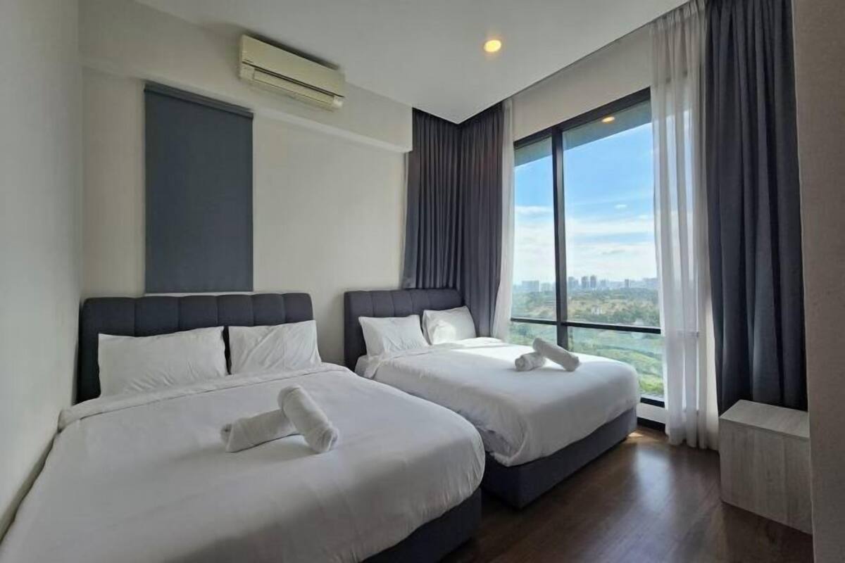 Une chambre d’hôtel avec deux lits, une grande fenêtre donnant sur la ville et un climatiseur fixé au mur.
