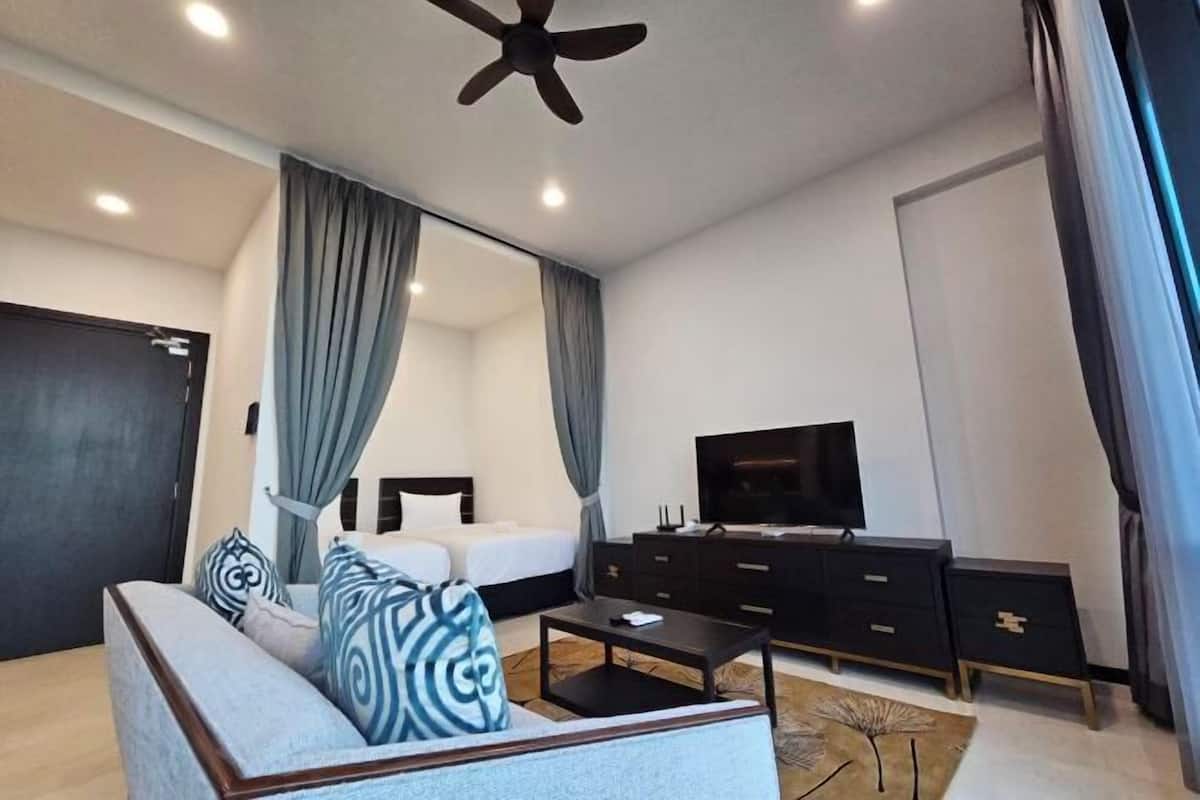 Une chambre d’hôtel moderne équipée d’un lit, d’un canapé, d’une télévision et d’un ventilateur de plafond.
