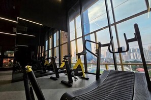 A gym with exercise equipment and large windows offering a city view. - Opus Residences by Star Haven (Kuala Lumpur)