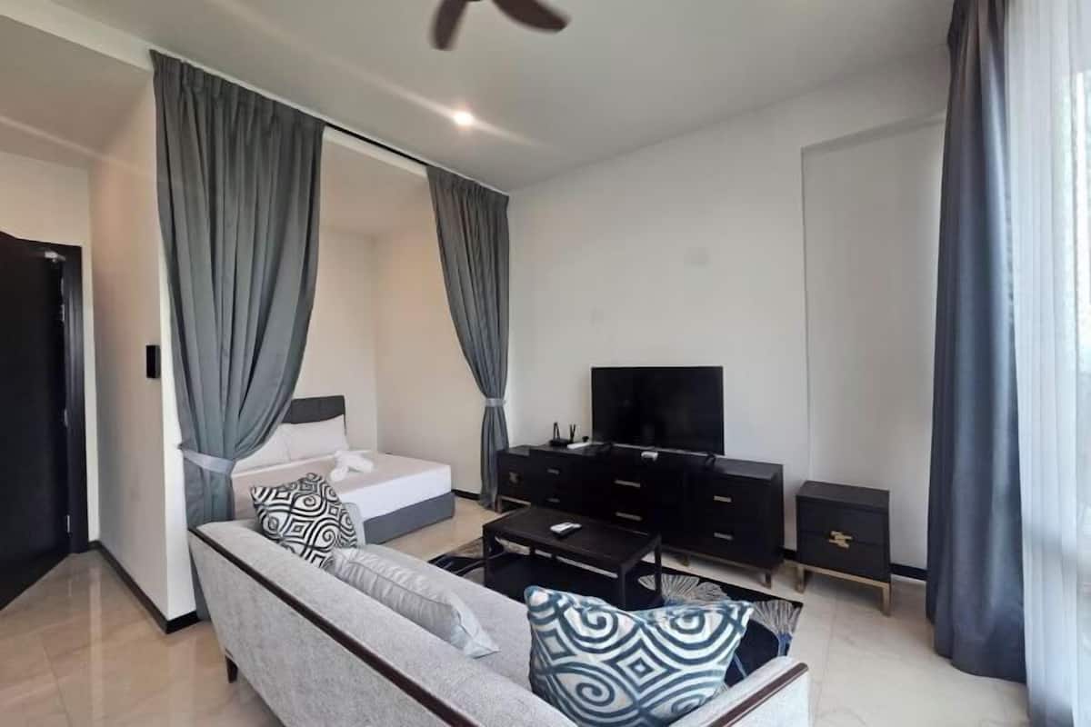 Un salon moderne avec un canapé, un téléviseur et un meuble de rangement noir pour appareils multimédias.