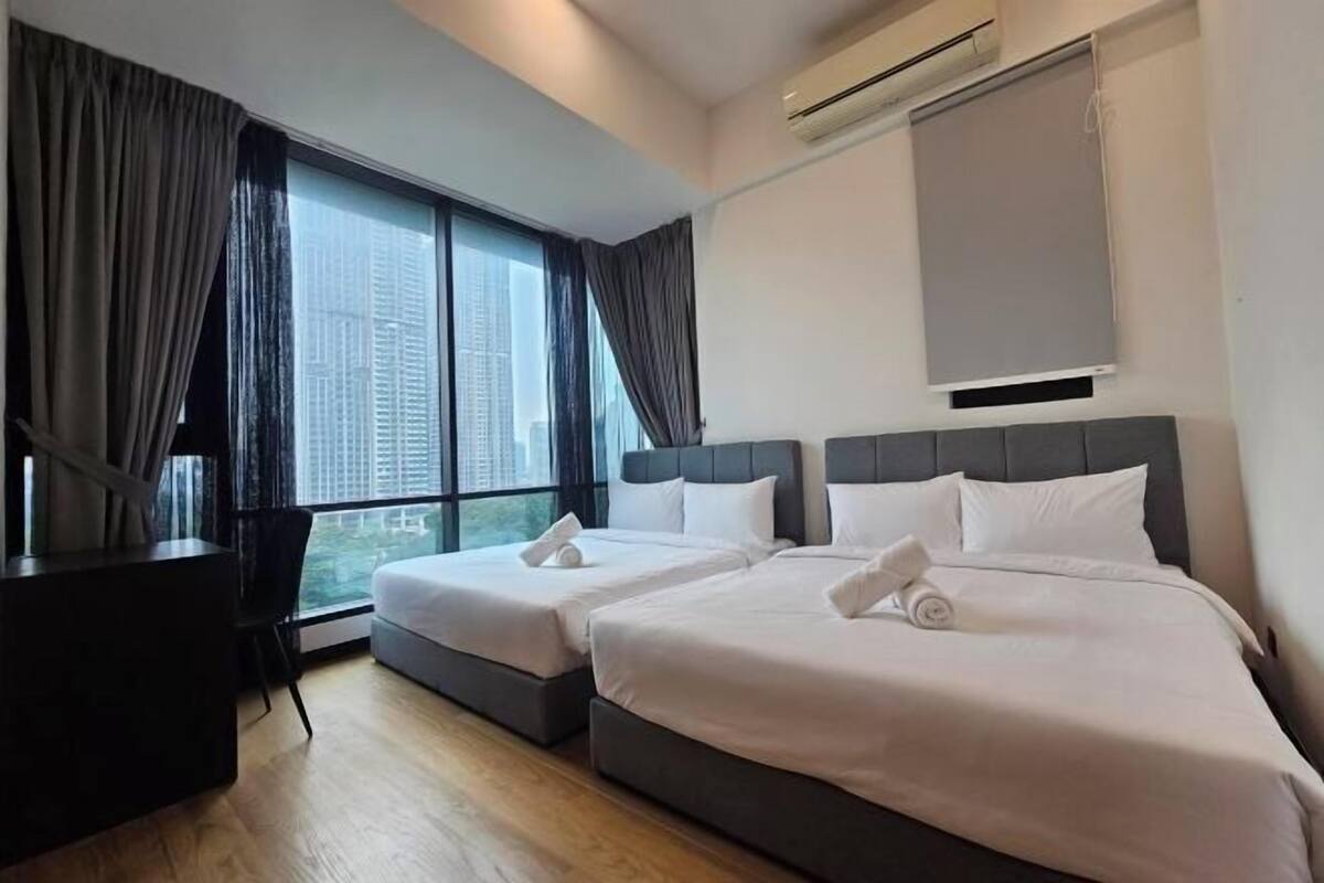Une chambre d’hôtel avec deux lits, un bureau et une grande fenêtre avec des rideaux.