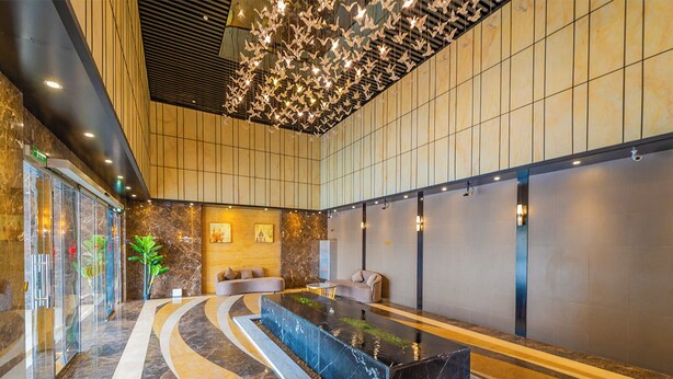 A modern lobby with a reception desk, seating area, and a unique ceiling design. - Lux JVT Resort Pools Spa Gym Kids Play (Dubai)