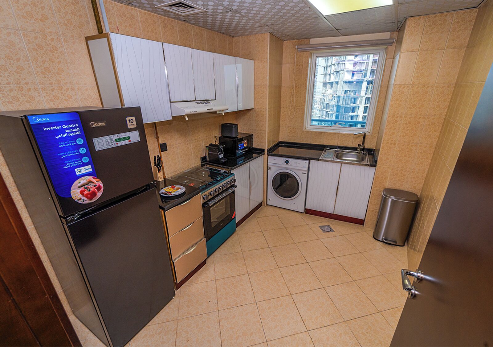 A compact kitchen with a refrigerator, stove, microwave, and washing machine.