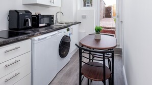A compact kitchen with a dishwasher, microwave, and a small table with a plant. - Modern Studio w/private Kitchen, Bathroom & Garden (Basildon)