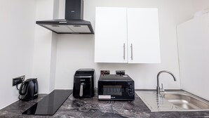 A modern kitchen with a built-in stove, a coffee maker, a microwave, and a sink. - Modern Studio w/private Kitchen, Bathroom & Garden (Basildon)