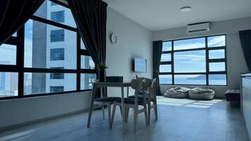 Ein modernes Zimmer mit großem Fenster, einem Esstisch, Stühlen, einer Couch und einem Fernseher.