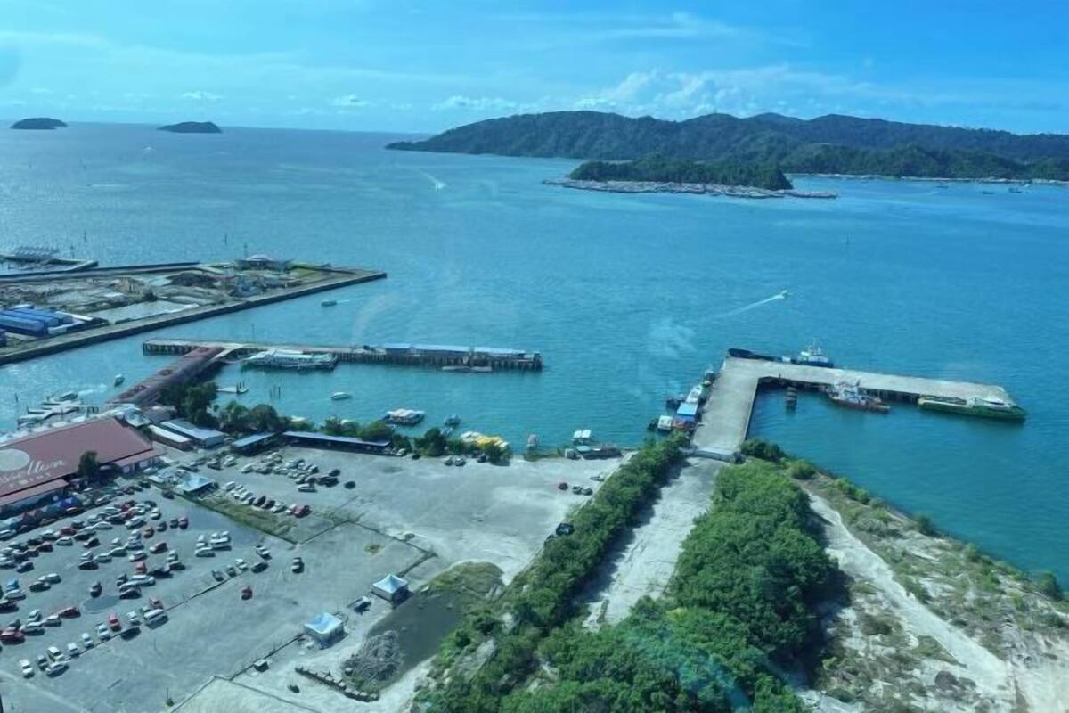 An aerial view of a coastal area with a marina, parking lot, and a restaurant.
