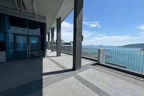An outdoor balcony with a view of the sea and a building with glass doors. - Jesslton quay Dream stay (Kota Kinabalu)