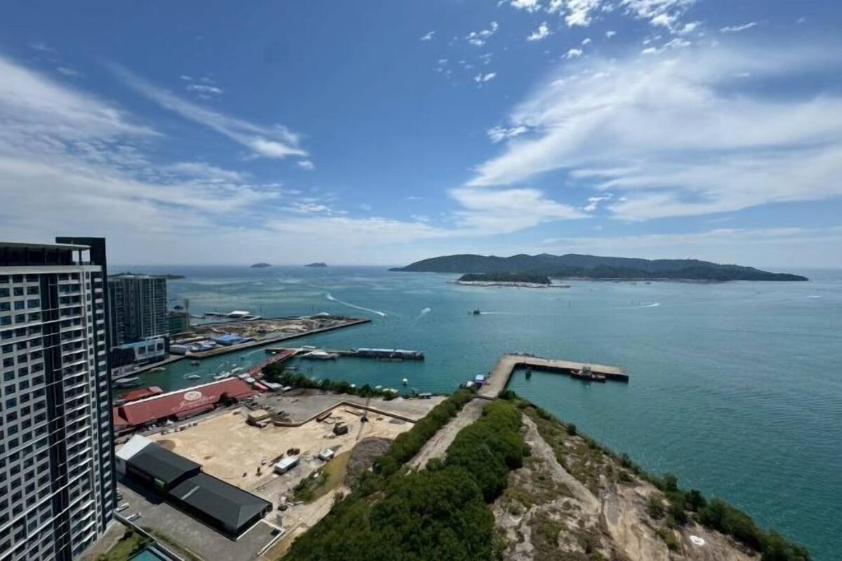 A coastal view with a marina, a large building, and a distant island.