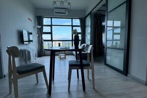 A modern hotel room with a large window, a flat-screen TV, and a dining area with chairs. - Jesslton quay Dream stay (Kota Kinabalu)