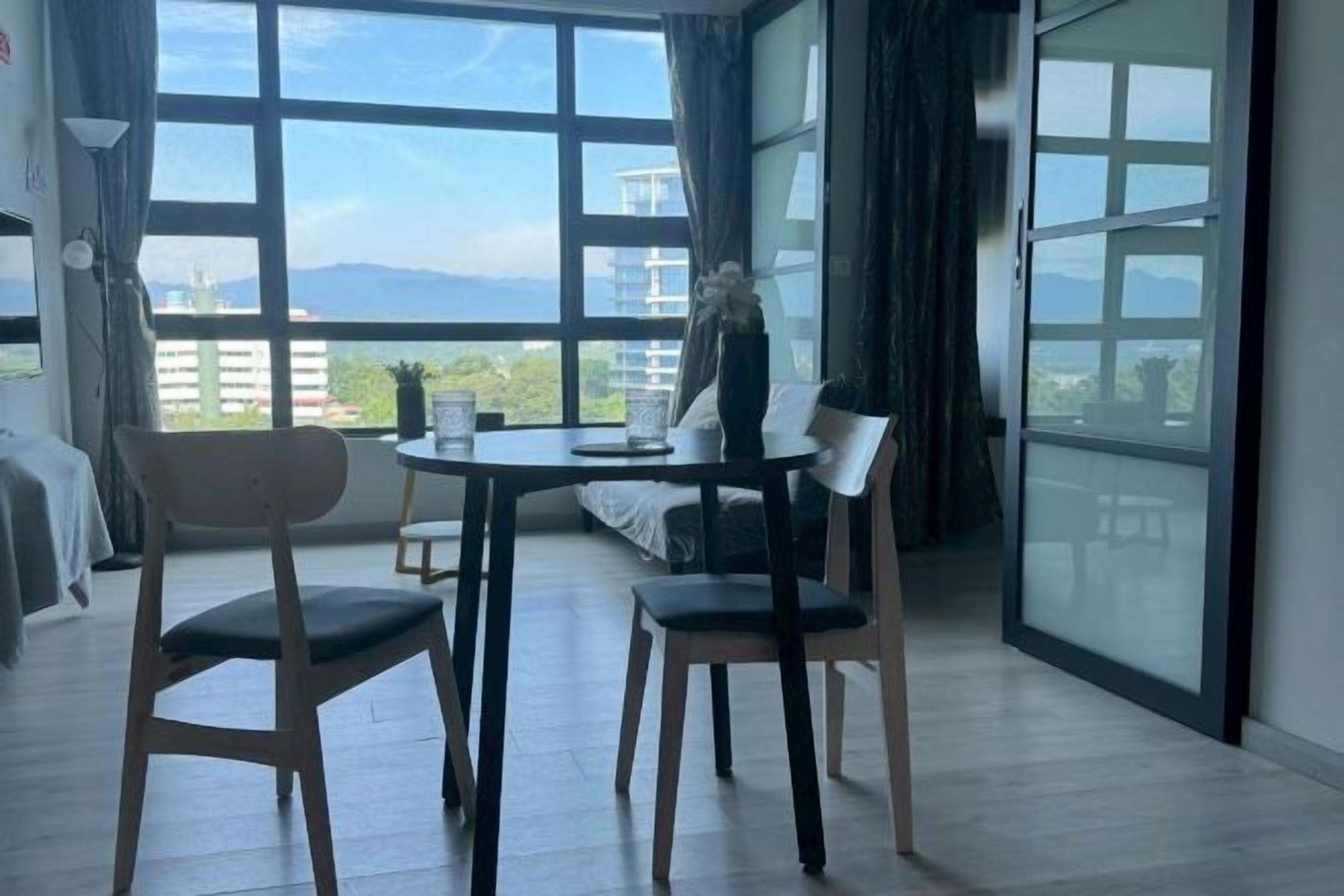 Quarto com varanda, mesa de jantar com cadeiras e vista para o exterior.