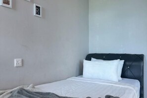 A single bed with a black headboard, white bedding, and a gray blanket. - Jesslton quay Dream stay (Kota Kinabalu)