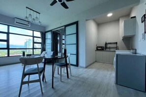 A modern kitchen with a dining area, large windows, and a view of the city. - Jesslton quay Dream stay (Kota Kinabalu)