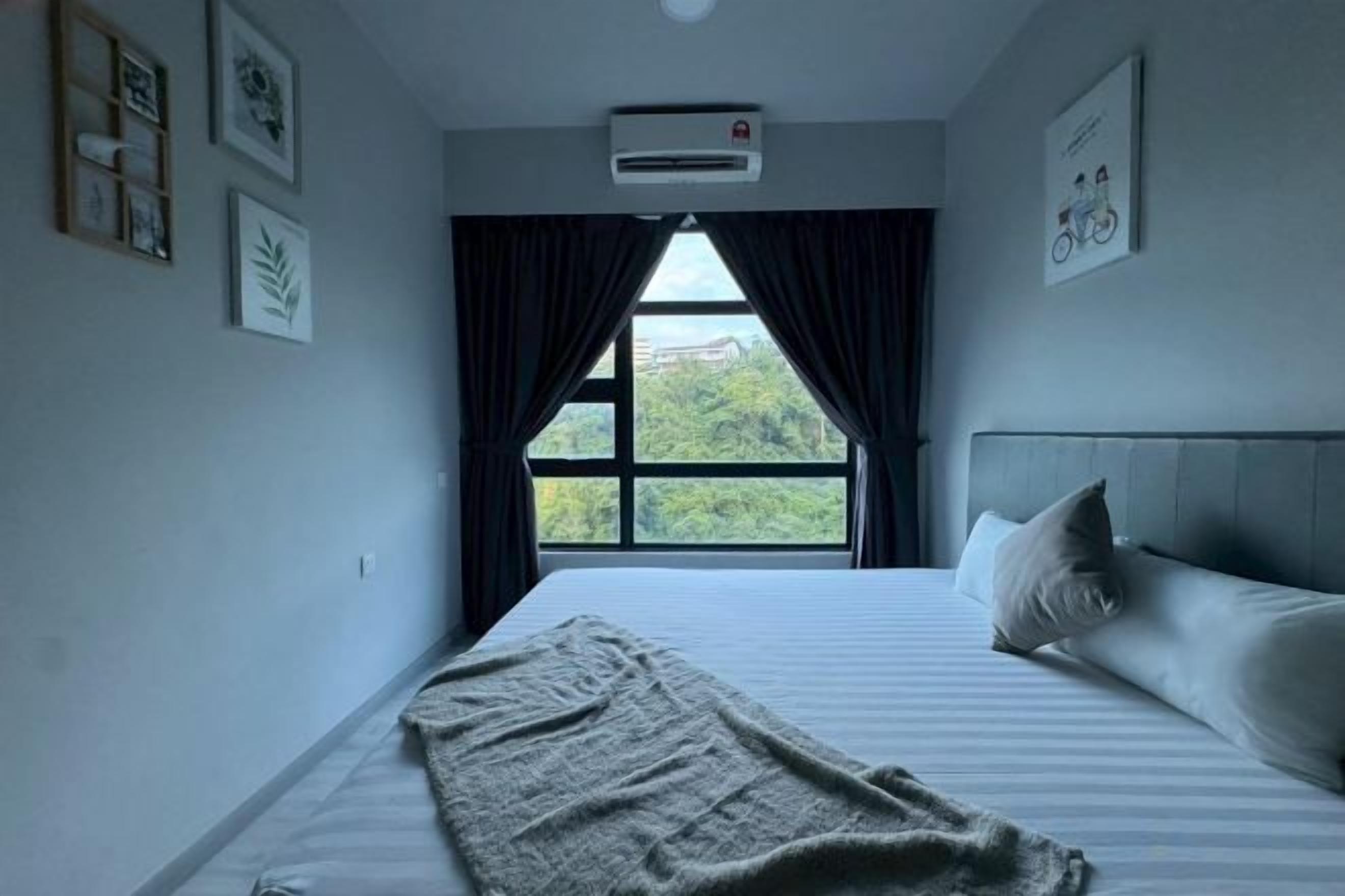 A bedroom with a large bed, a window with curtains, and a wall-mounted air conditioner.