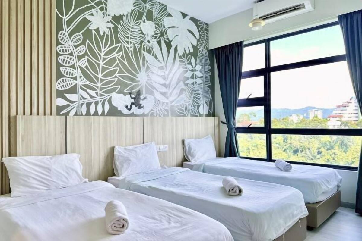 A hotel room with two beds, a large window with a view, and a wall mural.