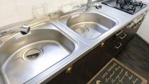 A kitchen with two stainless steel sinks, a gas stove, and a chalkboard with menu items. - -W- Vacation Rental (Nagoya)