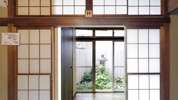 A traditional Japanese-style entrance with sliding doors, a tiled floor, and a small garden visible through the doorway. - -W- Vacation Rental (Nagoya)