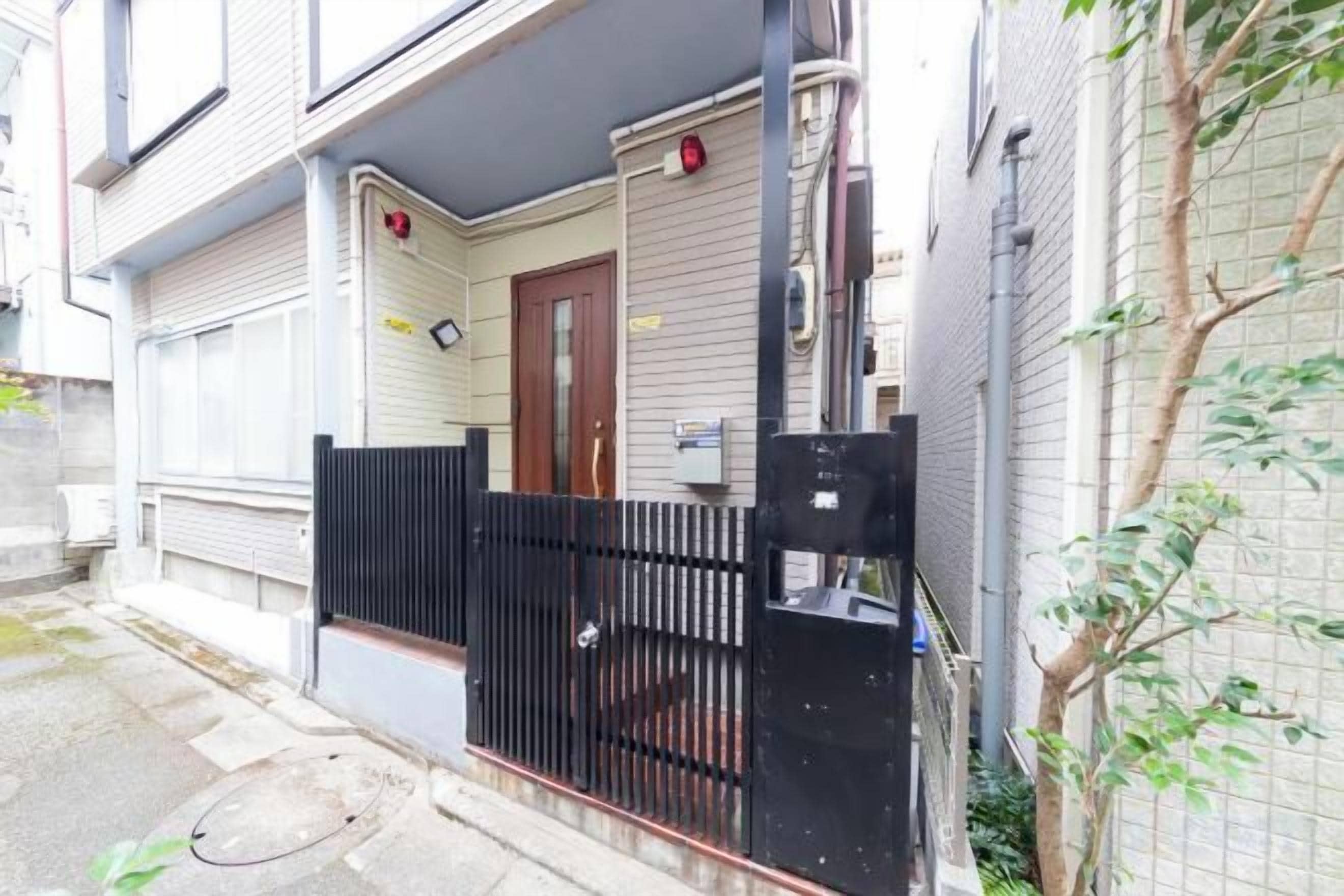 A residential building with a gated entrance, a door, and a small porch area.