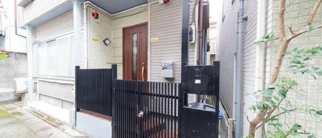 A residential building with a gated entrance, a door, and a small porch area.