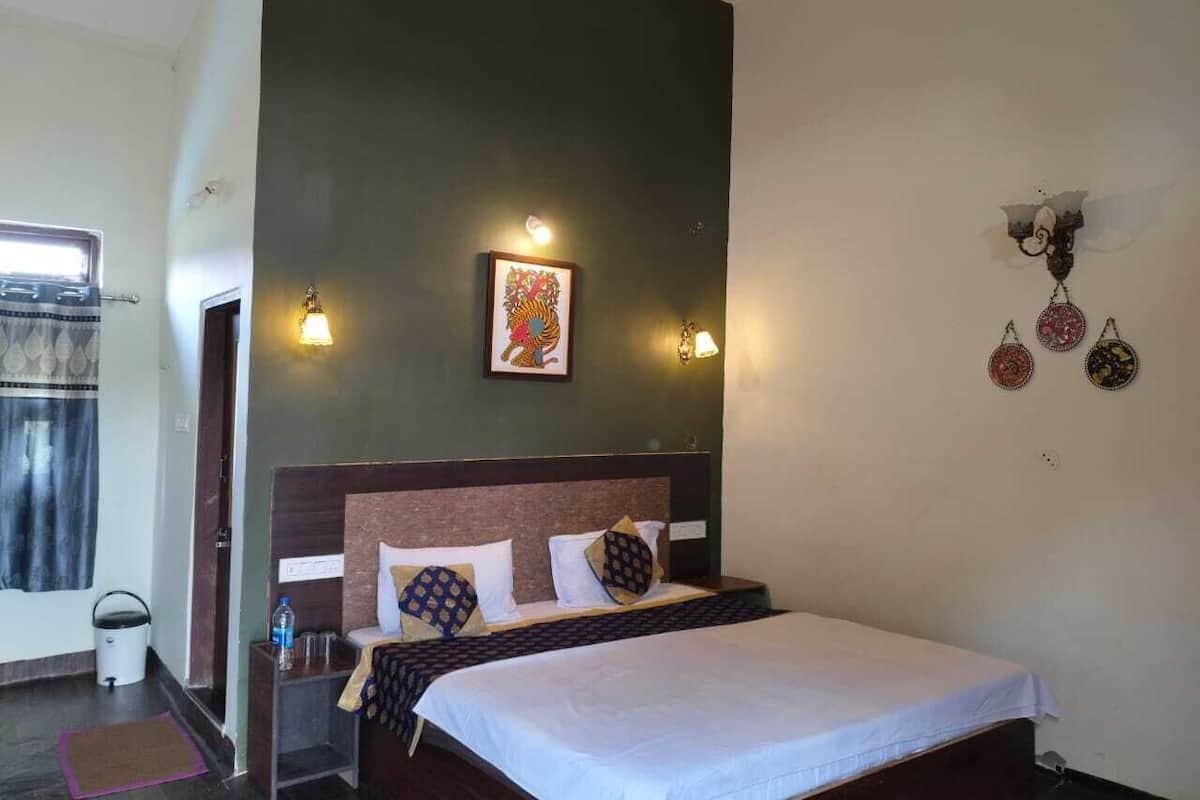 A hotel room with a bed, a nightstand, a wall-mounted light, a ceiling fan, and a window with curtains.