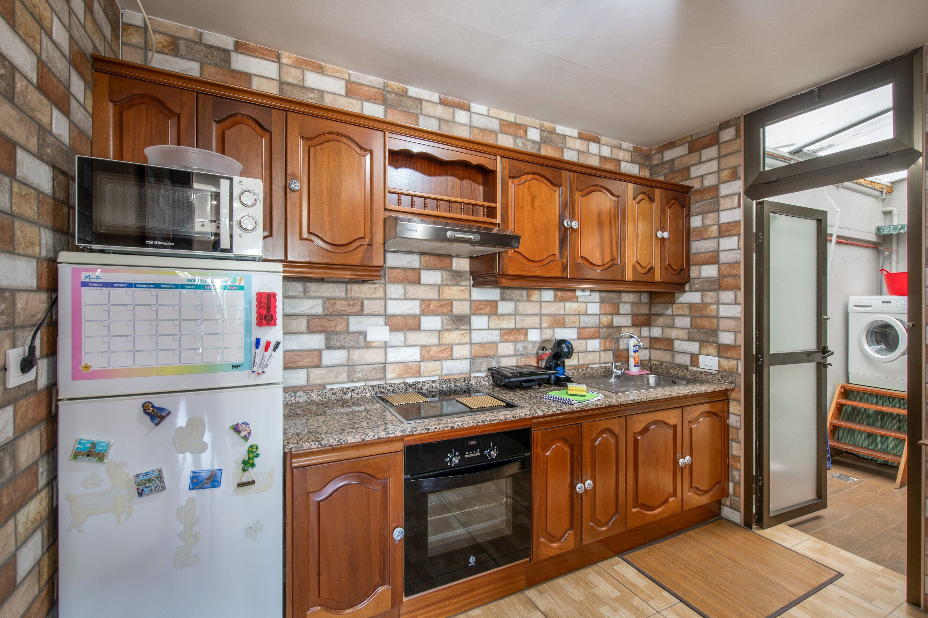 Una cocina con gabinetes de madera, un microondas, un refrigerador y un lavavajillas.