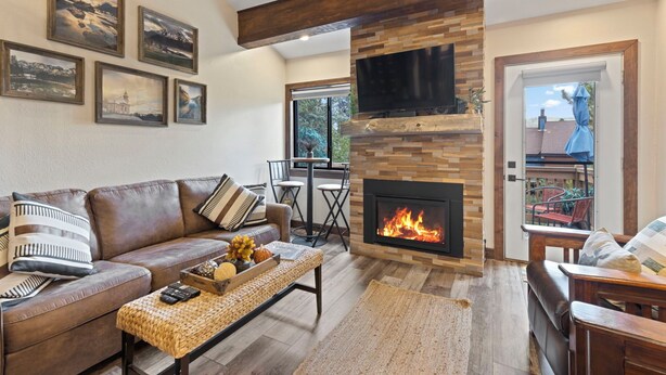 A cozy living room with a fireplace, a sofa, a coffee table, and a TV mounted on the wall. - The Retreat #6 (Breckenridge)