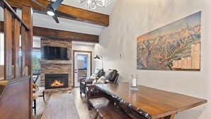 A cozy living room with a fireplace, wooden furniture, and a large painting on the wall. - The Retreat #6 (Breckenridge)