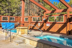 A wooden pool area with a clear pool, steps leading into the water, and a wooden pergola overhead. - The Retreat #6 (Breckenridge)
