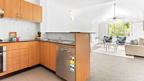 A modern kitchen with wooden cabinets, a dishwasher, and a dining area with a sofa and chairs.