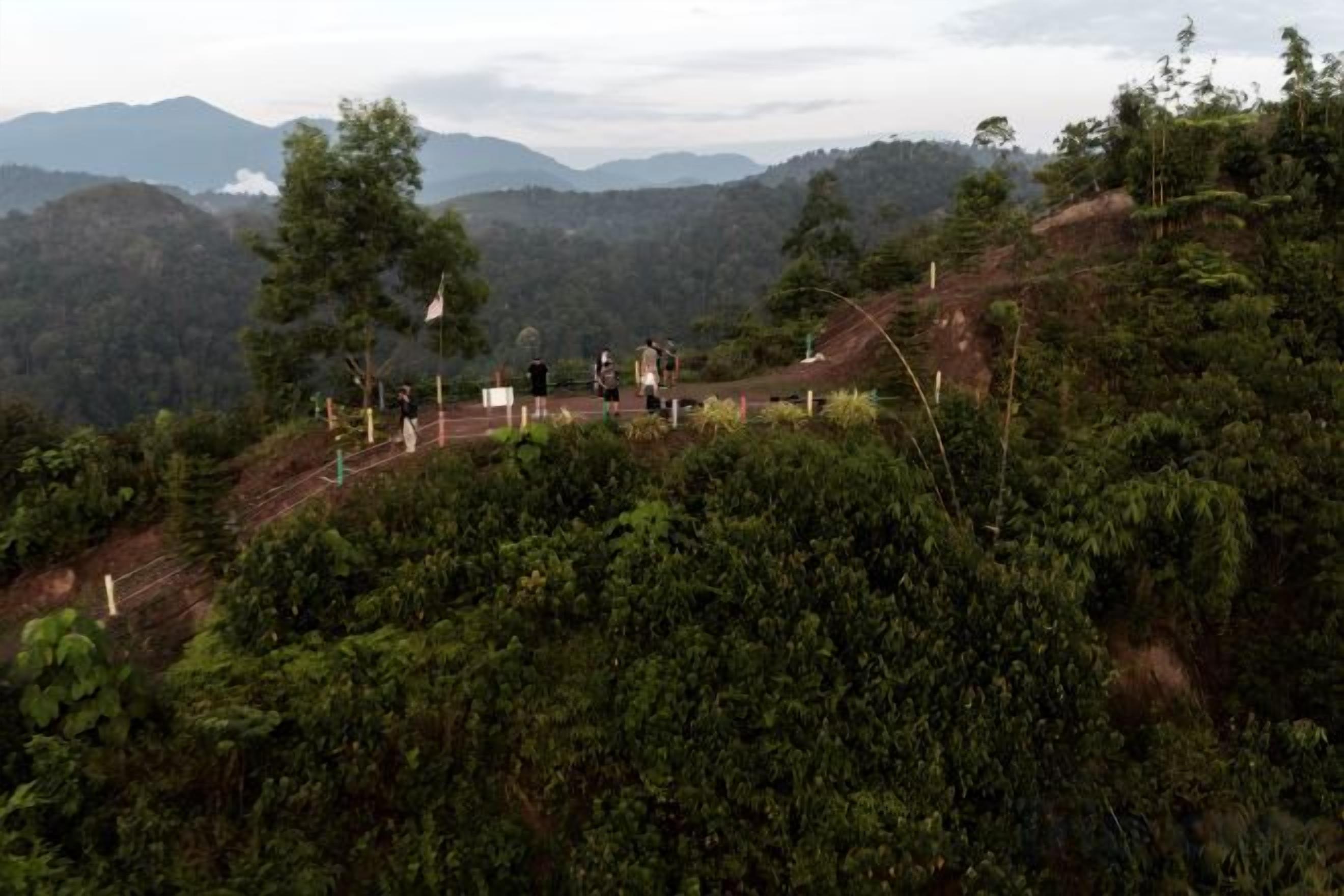 A mountainous landscape with a clear sky, a winding road, and a few people walking.