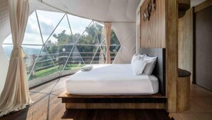 Ein Schlafzimmer mit großem Fenster, einem Bett und Holzdielen.
