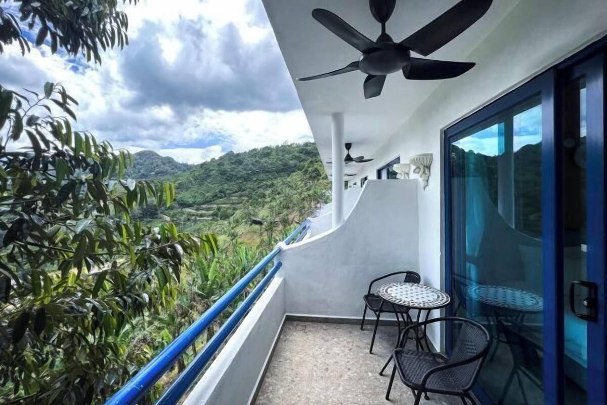 A balcony with a ceiling fan, a small table with chairs, and a glass door leading to a room.