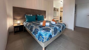 A bedroom with a bed, bedside lamps, a wardrobe, and a hanging light fixture.